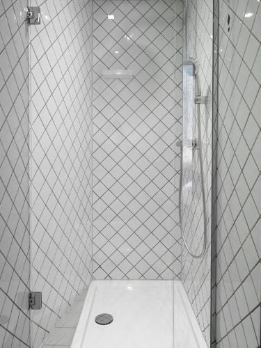 a white tiled bathroom with a shower with a toilet at Kaboom Maastricht in Maastricht