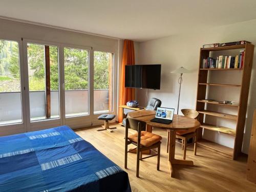 a bedroom with a bed and a desk with a laptop at Obm See in Davos Wolfgang