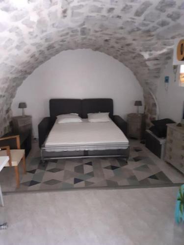 a bedroom with a bed in a stone wall at Studio idéal pour vos vacances in Saint Alban Auriolles