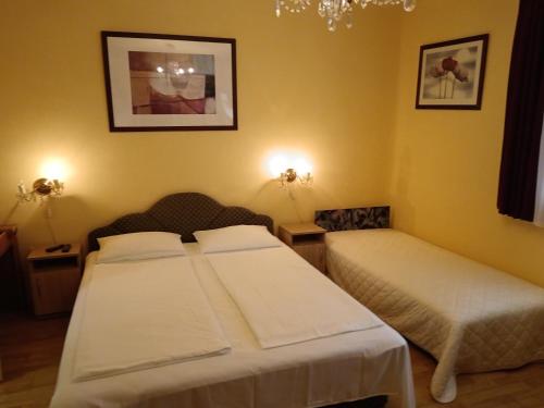 a bedroom with two beds and a chandelier at Margó Vendégházak 2 in Hajdúszoboszló