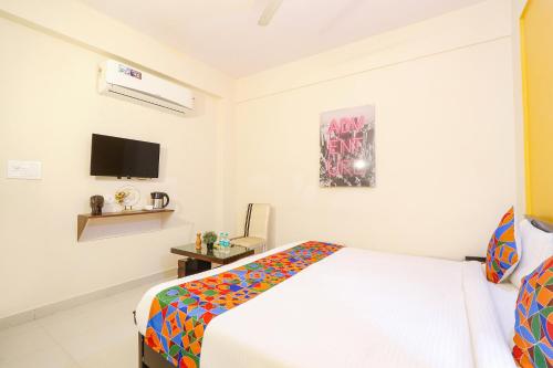 FabHotel Namaha Suites في حيدر أباد: غرفة نوم مع سرير وتلفزيون على الحائط