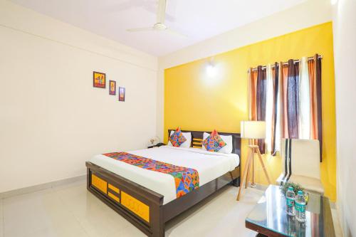 FabHotel Namaha Suites في حيدر أباد: غرفة نوم بسرير وجدار اصفر