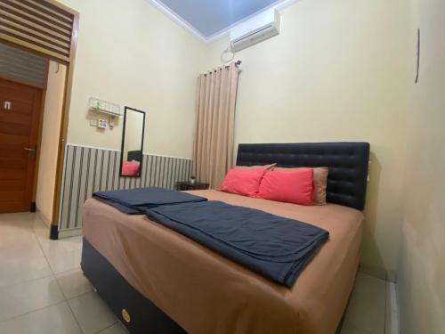 um quarto com uma cama grande com almofadas vermelhas e azuis em Rumah Kemuning Mataram em Mataram