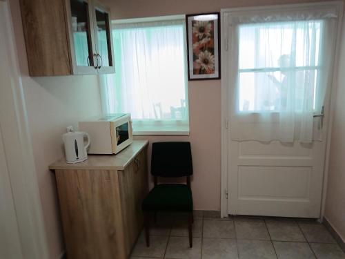 a small kitchen with a microwave and a door at Margó Vendégházak 2 in Hajdúszoboszló