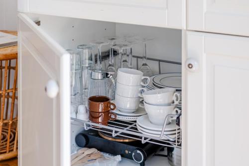 a cabinet filled with dishes and cups and plates at Coastal Cabin Engure in Engure