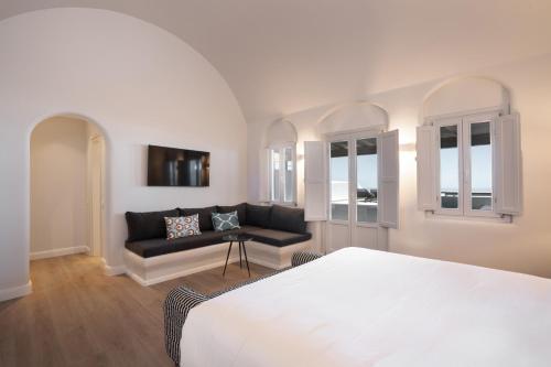 ein Schlafzimmer mit einem Bett und einem Sofa in der Unterkunft NĒRO Suites by NOMÉE Hospitality Group in Imerovigli