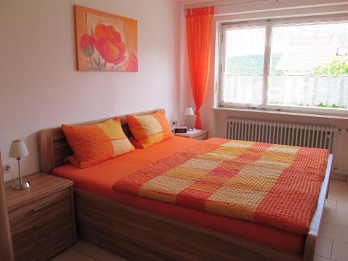 1 cama en un dormitorio con ventana y colcha en Ferienwohnung-STREUTALBLICK, en Fladungen