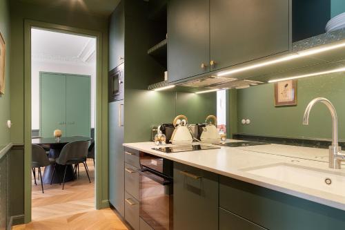 - une cuisine avec des murs verts, un évier et une table dans l'établissement Paris Home Collection Serviced Apartments in Opéra - Rue Saint-Lazare, à Paris