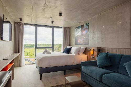 a bedroom with a bed and a blue couch at Ki Space Hotel & Spa - près de Disneyland Paris in Serris