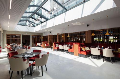 a restaurant with tables and chairs and a glass ceiling at Ki Space Hotel & Spa - près de Disneyland Paris in Serris