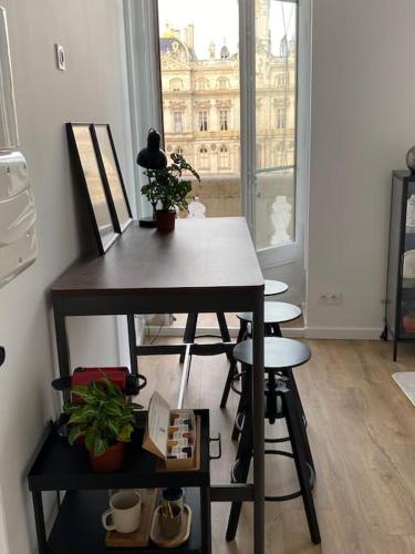 - une table et des tabourets dans une chambre avec fenêtre dans l'établissement Grand Balcon Place des Terreaux, à Lyon