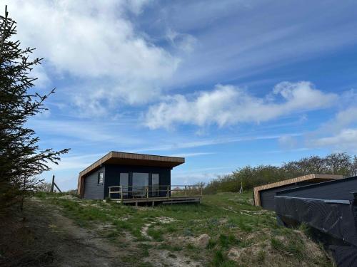 a small house on a hill next to a field at Cozy Tiny House In Nature - Holiday Home C in Sejerby