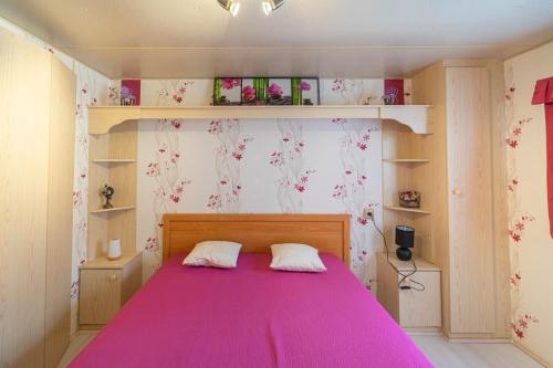 - une chambre avec un grand lit rose et des étagères dans l'établissement Mobil Home Willerby, à La Tremblade