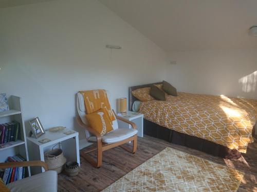 a bedroom with a bed and a chair in it at 2 Bedroom Family Cottage Dog Friendly Edern North Wales in Ederyn