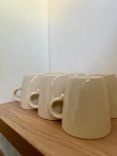 quatre tasses à café blanches posées sur une étagère en bois dans l'établissement Le Winston Churchill, Rennes Ouest, à Rennes