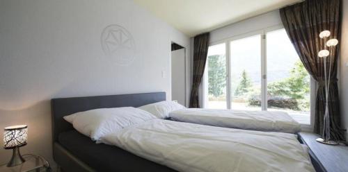 a bedroom with two beds and a large window at Chasa Diala, sonnig und schönste Aussicht, Wohnung Sirena in Scuol