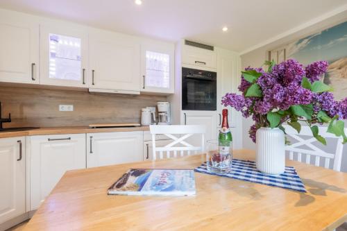 a kitchen with a table with a vase of purple flowers at Uns Lütje Hus - Sellin in Sellin