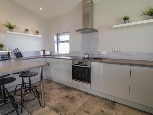 a kitchen with white cabinets and a wooden table at Tory Island View in Mín Lárach