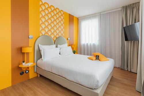 a bedroom with a large white bed with yellow walls at Appart'City Collection Paris Vélizy in Vélizy-Villacoublay