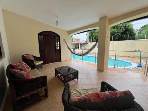 a living room with chairs and a hammock next to a pool at Casa agradável com piscina, ar condicionado e churrasqueira in Natal