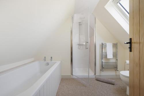 a white bathroom with a tub and a toilet at The Stables in Mickleton