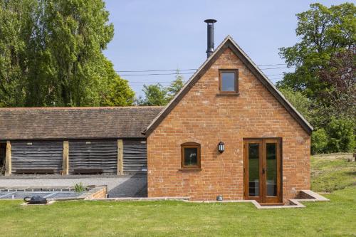 a red brick house with a grass yard at The Stables in Mickleton