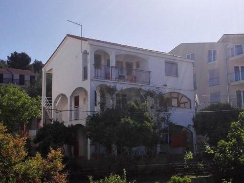 um grande edifício branco com árvores em frente em Ferienwohnung mit Meerblick von der Terrasse für bis zu sechs Personen em Trogir