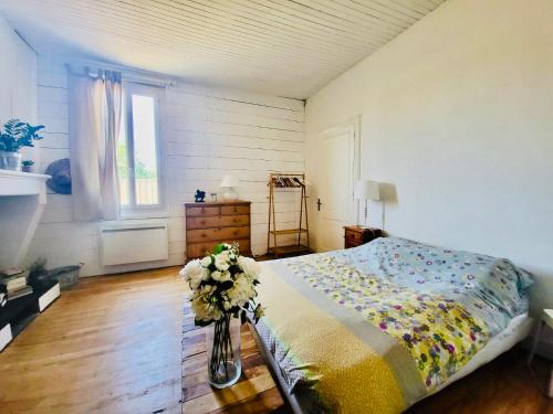 - une chambre avec un lit et un vase de fleurs dans l'établissement Entre pin et ocean carcans ville, à Carcans