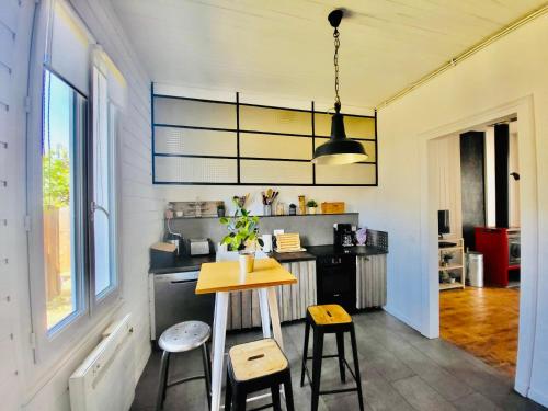 une cuisine avec une table et des tabourets dans une pièce dans l'établissement Entre pin et ocean carcans ville, à Carcans