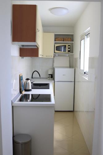 a small white kitchen with a stove and refrigerator at Neda Apartmani in Mali Lošinj