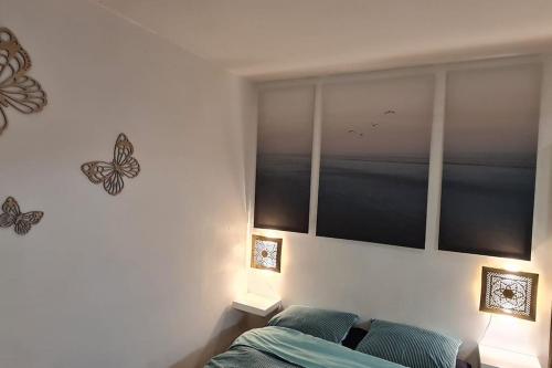 - une chambre avec un lit et des papillons sur le mur dans l'établissement Superbe appartement au cœur du village, à Marseillan
