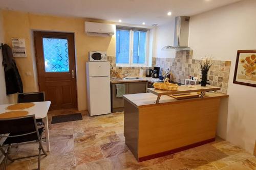 une cuisine avec une table et un réfrigérateur blanc dans l'établissement Superbe appartement au cœur du village, à Marseillan