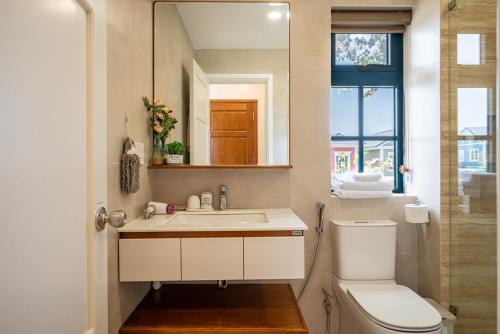 a bathroom with a sink and a toilet and a mirror at AnnA Villa - Novaworld Phan Thiết in Bình Tú