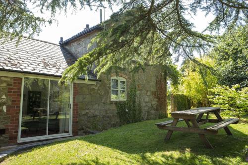 a picnic table in front of a stone house at Courtyard Cottage in Oswestry
