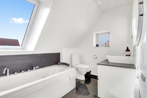 ロッケンにあるLovely Holiday Home For Rent, Josefines Have 17の浴槽、トイレ、窓のあるバスルーム