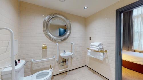 a bathroom with a toilet and a sink and a mirror at The Coal Exchange Hotel in Cardiff