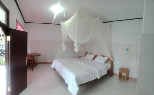 a bedroom with a bed with white sheets and curtains at Volcano 3 hotel in Kintamani