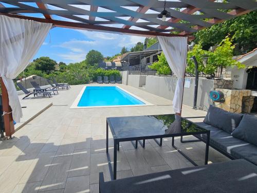 a patio with a table and a swimming pool at Holiday House Above with pool and summer kitchen in Klis