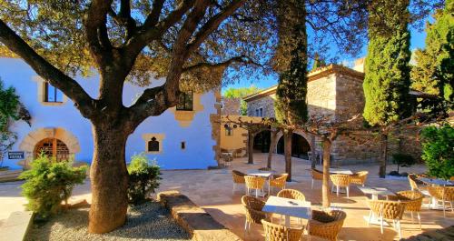 a courtyard with tables and chairs and a tree at AlliOli Boutique Hotel Spa in Castelló d'Empúries