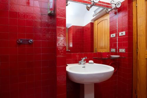 a red bathroom with a sink and a red tiled wall at Villa Gabbiani in Vignola Mare