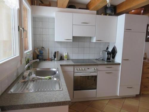 una cocina con armarios blancos y fregadero en Ferienwohnung Howart - b48611 en Ebnat