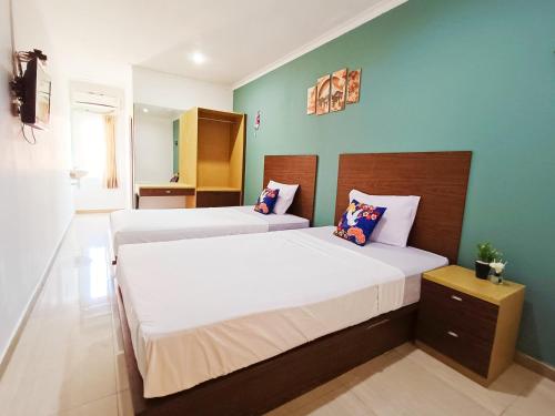 2 Betten in einem kleinen Zimmer mit grünen Wänden in der Unterkunft YUTAKA LG Dukuh Kupang in Surabaya