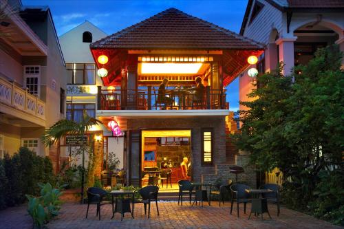 a building with a balcony with tables and chairs at Villa Orchid Garden Riverside Hoi An in Hoi An