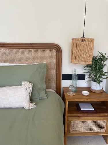 a bedroom with a bed with a night stand with a plant at Meraki in Polhena