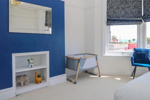a bedroom with blue walls and a desk and a chair at Breeze in Bognor Regis