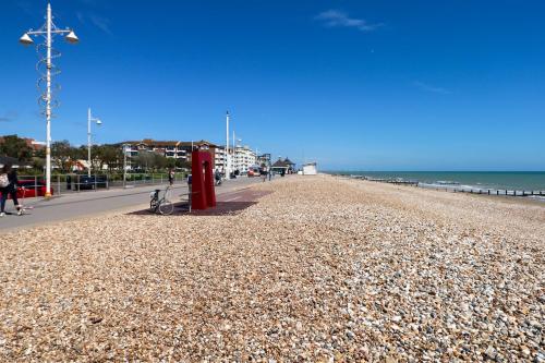 a beach with a red phone booth next to the ocean at Breeze in Bognor Regis