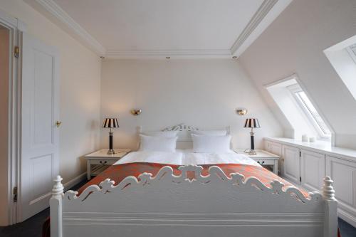 a white bedroom with a bed with two windows at Strönhof Kampen in Kampen