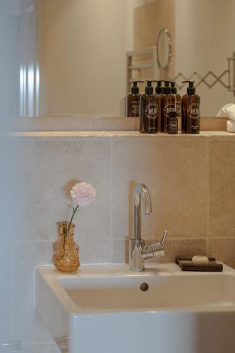 a bathroom sink with a vase with a flower in it at Strönhof Kampen in Kampen