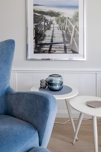 a blue chair and a table with a picture of a pier at Strönhof Kampen in Kampen
