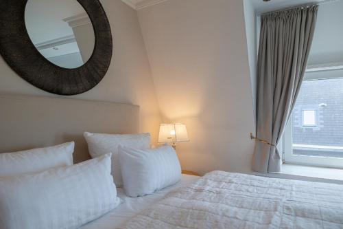 a bedroom with a bed with a mirror and a window at Strönhof Kampen in Kampen